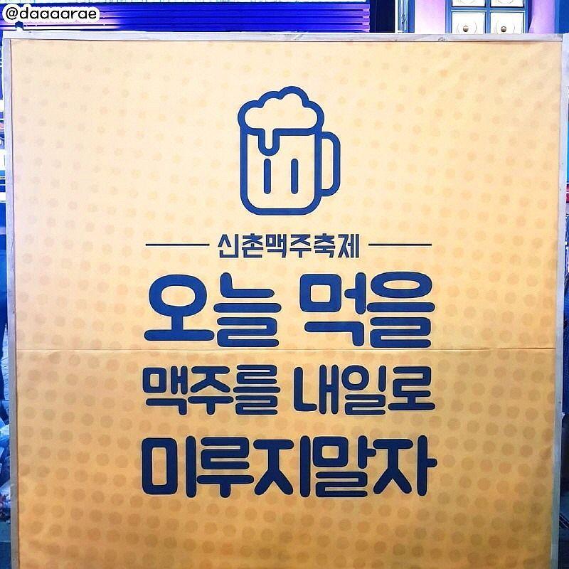 新村啤酒節的標語板，內容為諷刺拖延的文字，設計成黃色背景，突顯幽默感。