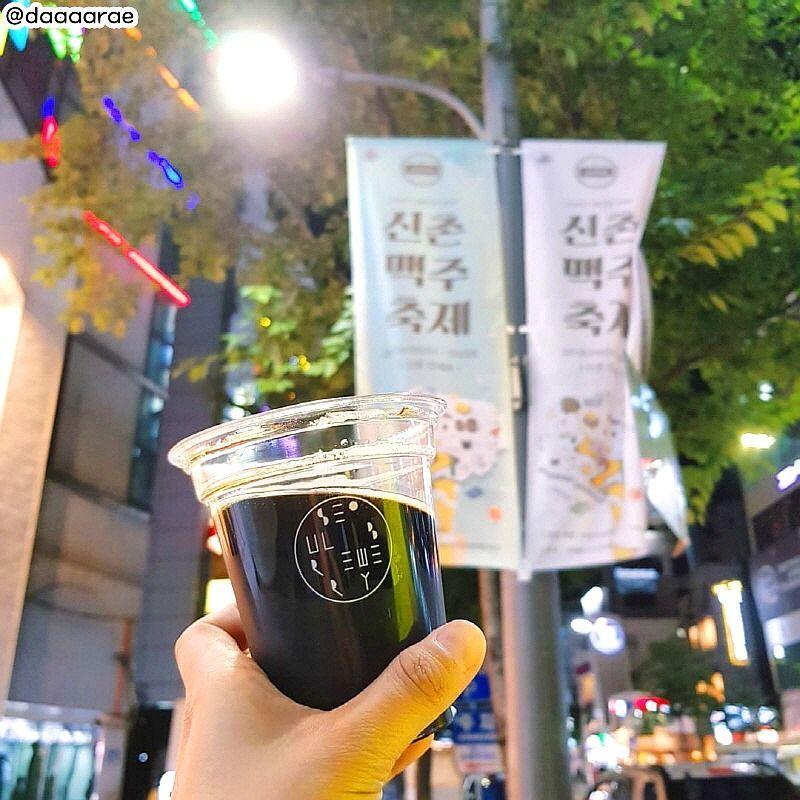 一杯由SEOUL BREWERY釀造的啤酒，高高舉起歡慶新村啤酒節的夜色。