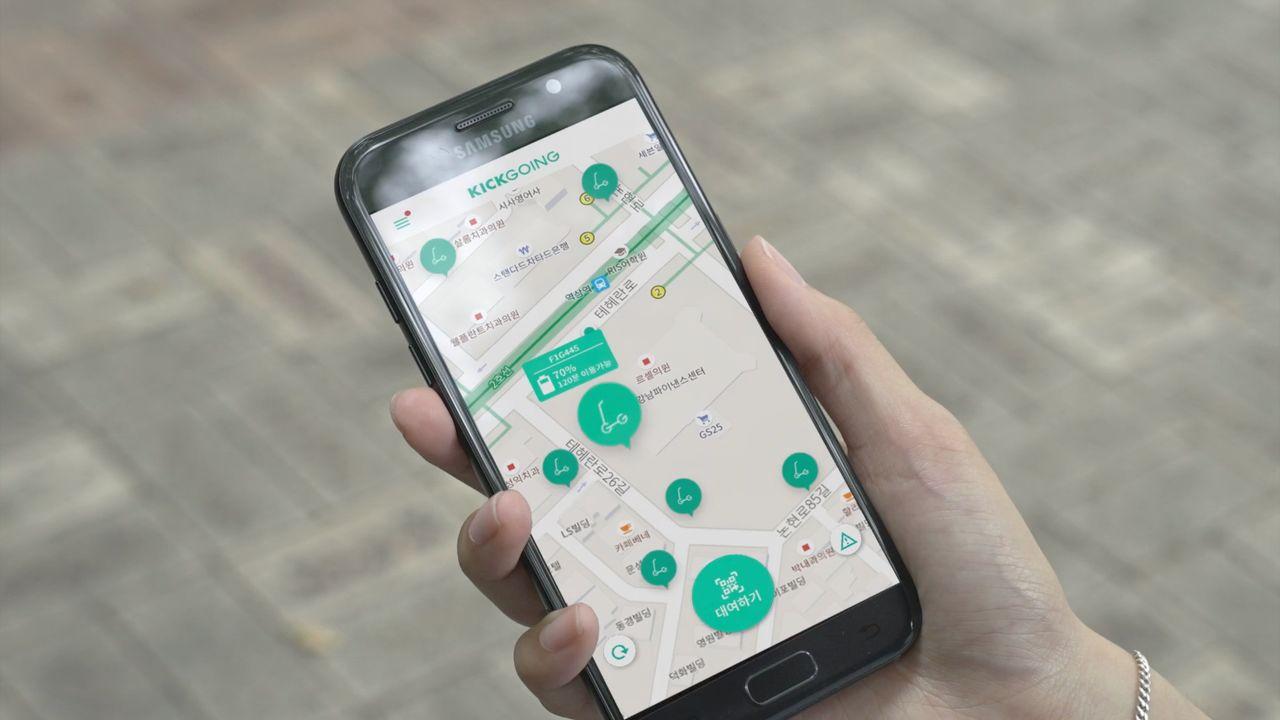 正在使用手機查看 KICKGOING 應用地圖，顯示附近可用滑板車的位置資訊。