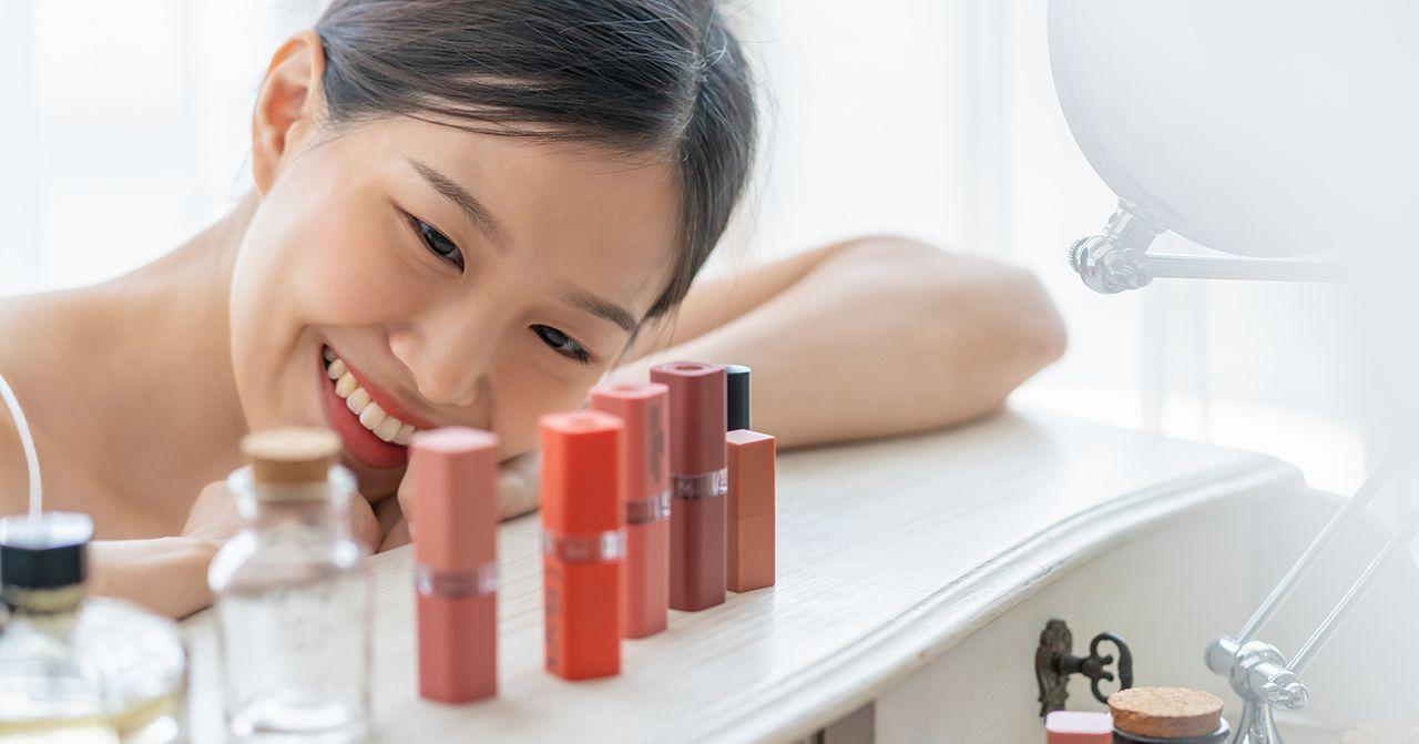 Variation of lipstick and beauty items on a table with a blurred face