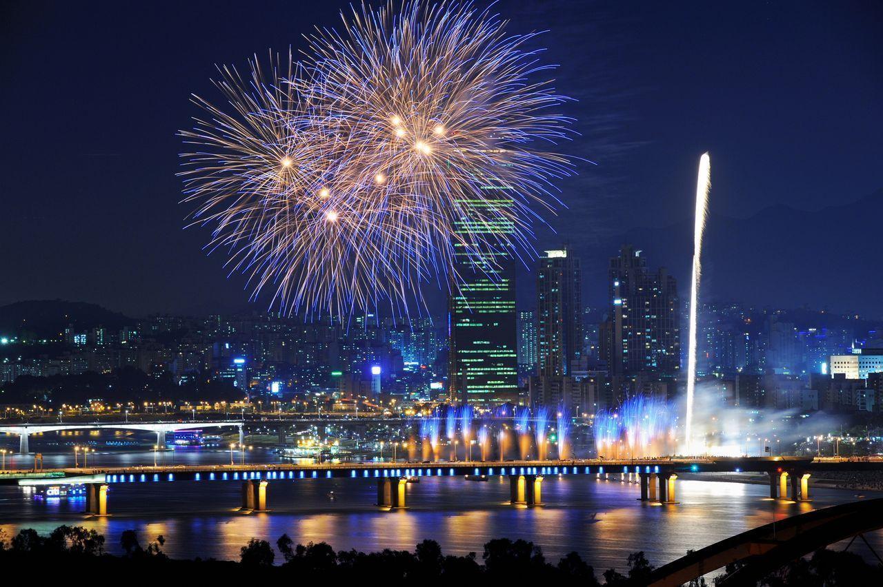 Spettacolo di fuochi d'artificio sullo sfondo del panorama notturno della città di Seoul, mentre il ponte Banpo è illuminato.