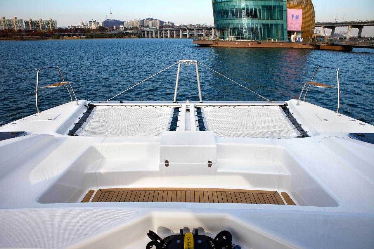 Yacht di lusso in una giornata di sole, ormeggiato vicino a uno spazio urbano moderno e rilassante con viste panoramiche.