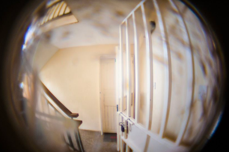 透過貓眼看到的走廊景象，提醒檢查門上的貓眼與電話是否正常。