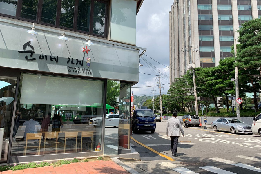 韓國首爾安國站附近，順美家店面的實景，旁邊有綠樹和行人，展現都市生活魅力。