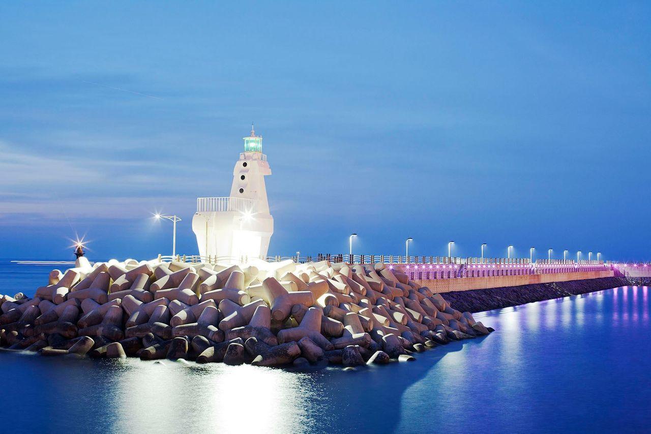 梨湖木筏燈塔在夜晚亮起燈光，照亮濟州市區的海岸線。