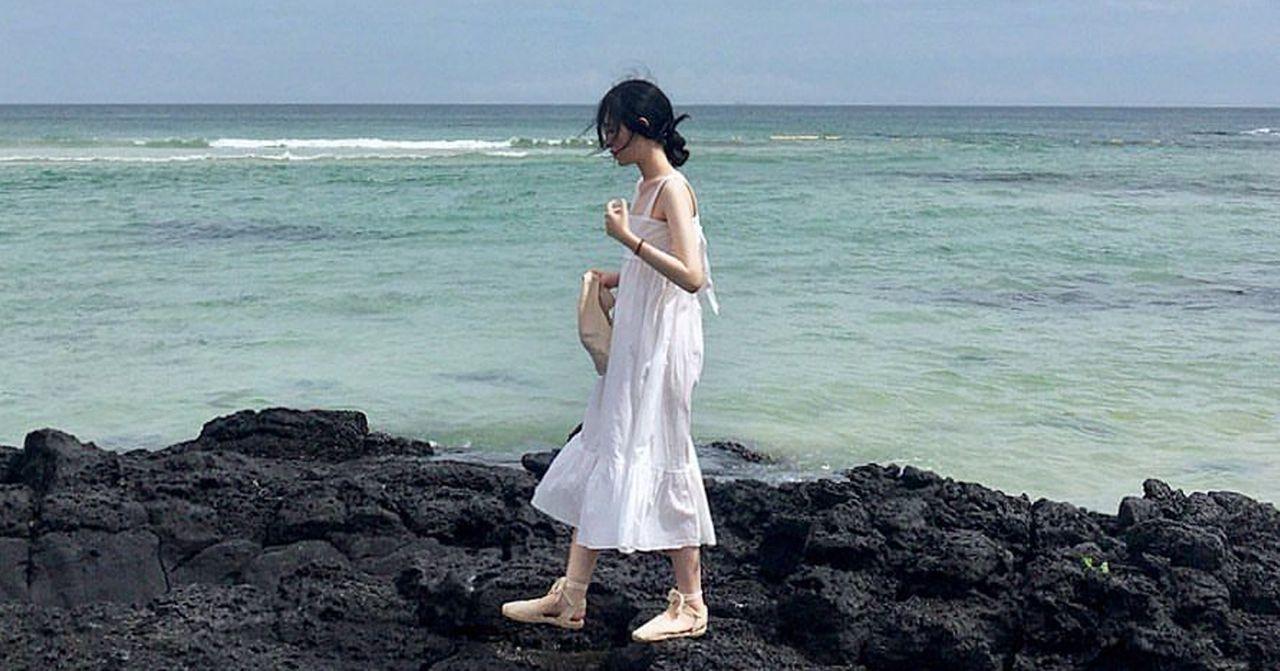 濟州島某海灘上，一個人站在黑色石頭上俯瞰浪潮。