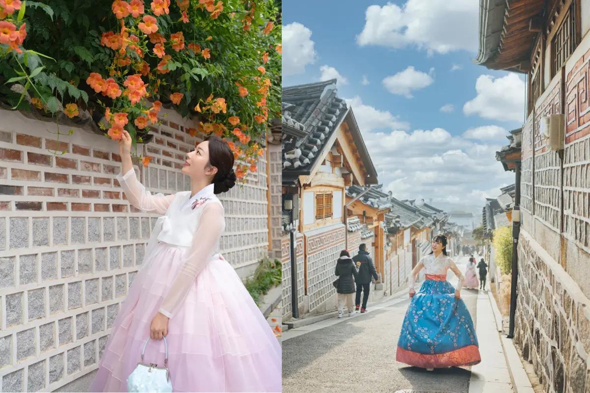 Street scene at Bukchon Hanok Village with a person admiring orange flowers while wearing a hanbok.