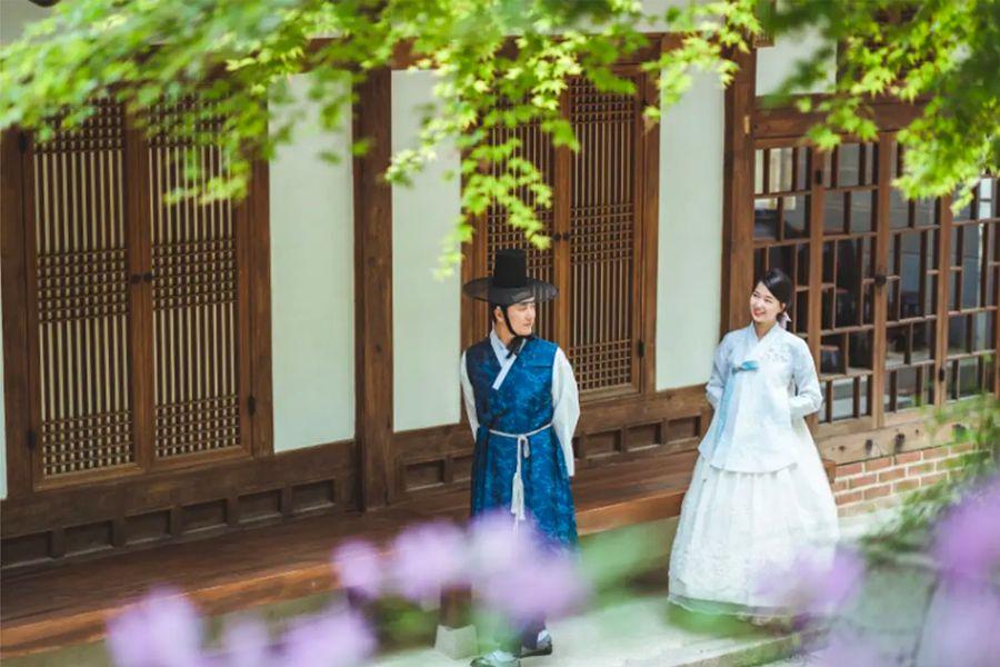 在戶外拍照的一對年輕情侶，背景是韓國的綠樹