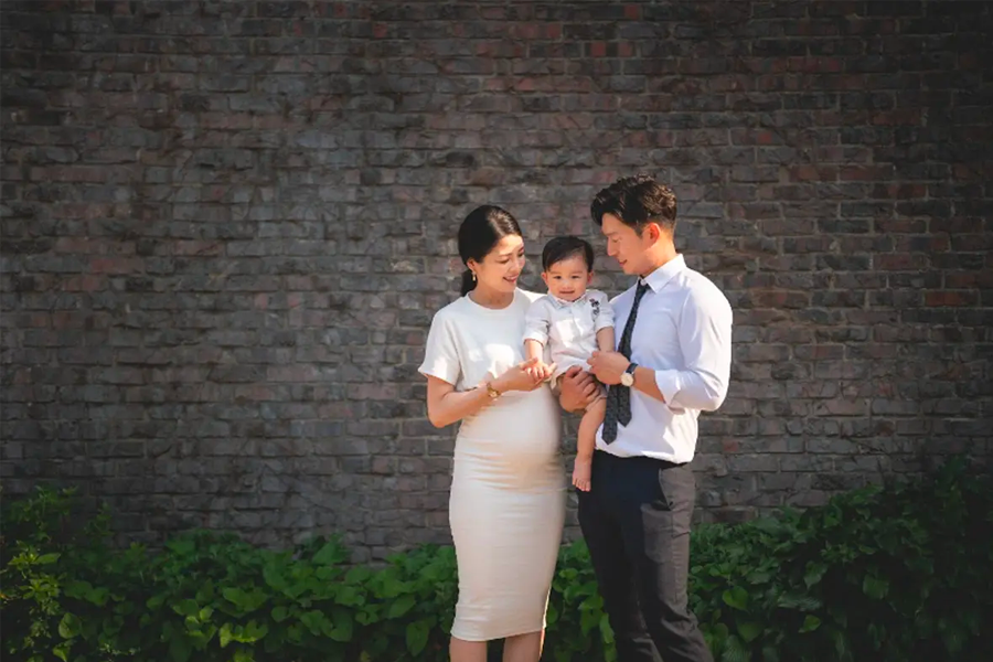 一家三口在磚牆前留下合照，氣氛溫馨