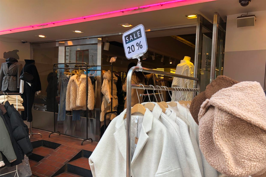韓國街頭的時尚商店,展示著各種大衣和夾克,提供秋冬時尚折扣,在誘惑顧客購買季節新品。
