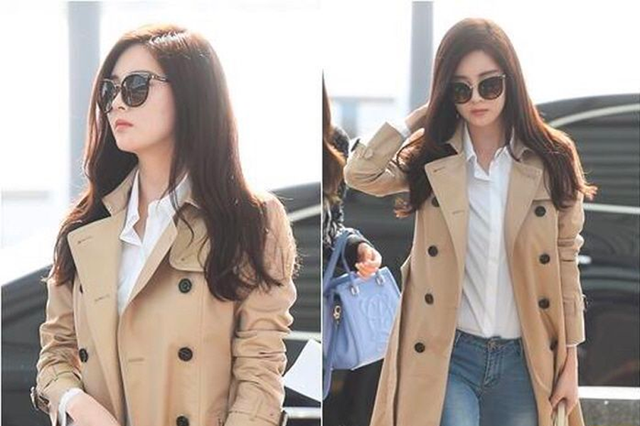 穿著時尚風衣和牛仔褲的女子走在首爾街頭，展現奢華的秋季穿搭風格。