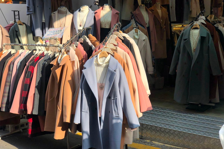 韓國街頭時尚精品店,入口旁排列著豐富多樣的大衣選擇,讓顧客能選擇秋冬時尚外套。