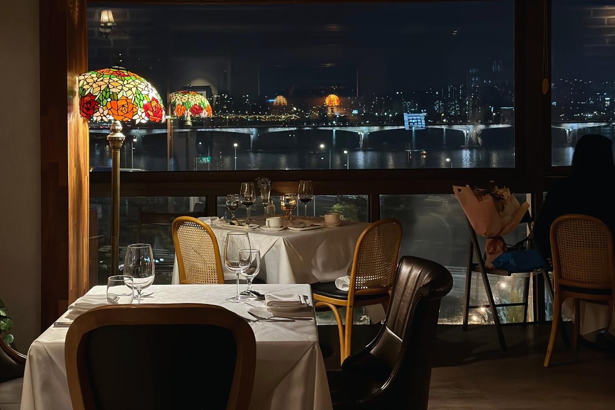Elegant restaurant in Seoul with a stunning view of Han River at night, perfect for romantic dinners.