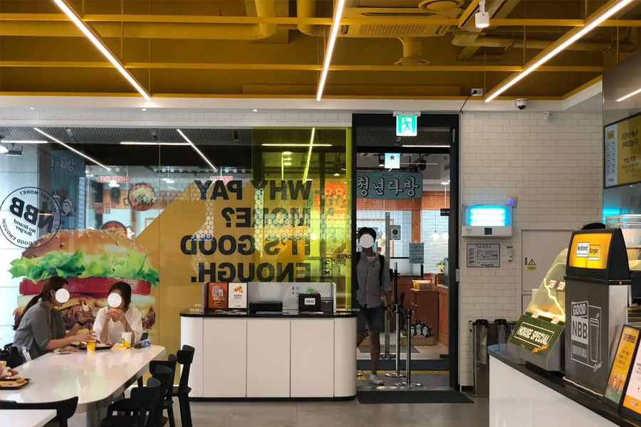 노브랜드 버거 내부의 테이블과 의자들이 배치된 다이닝 공간 사진