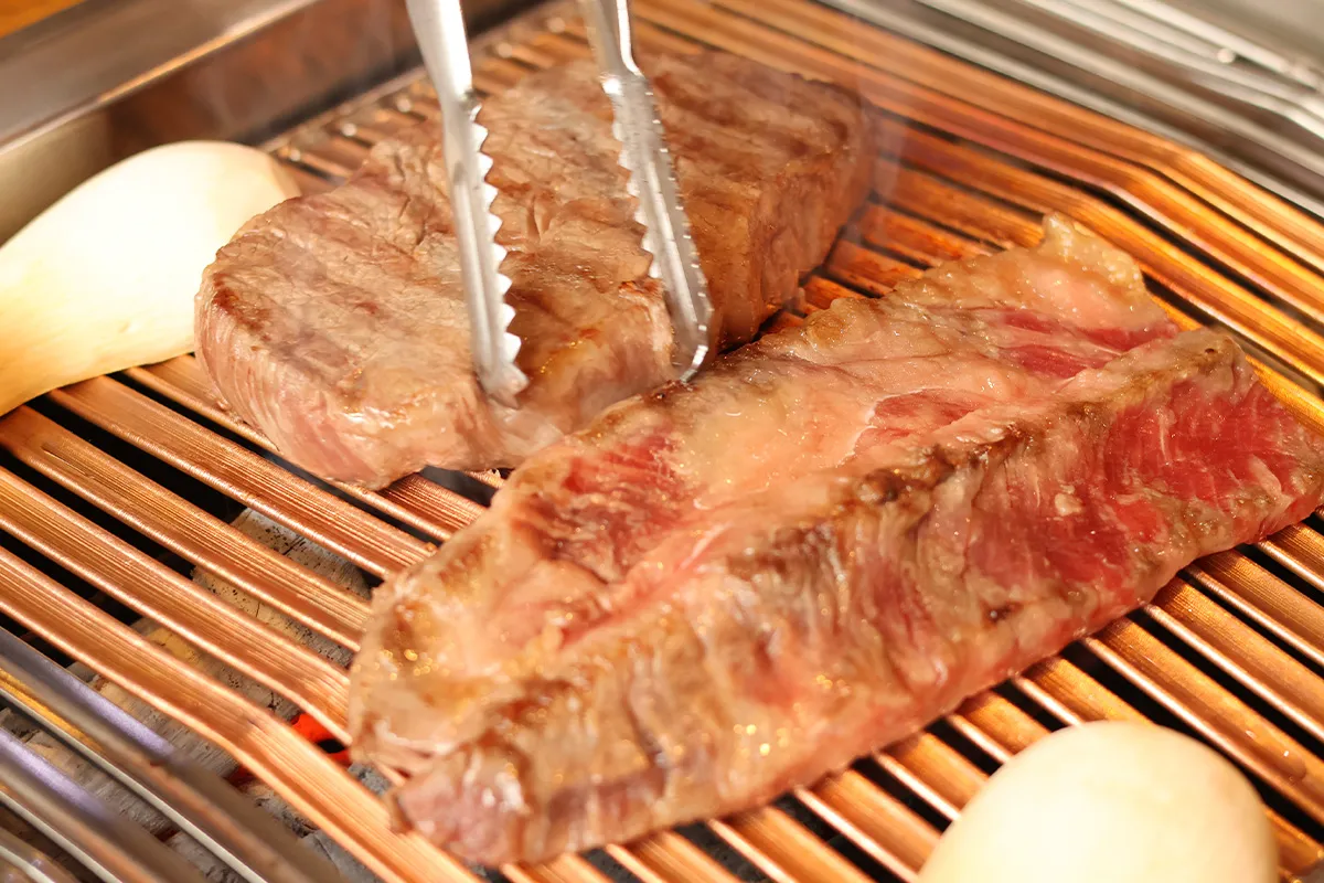 在Bo Reum Sae餐廳裡，新鮮有彈性的牛排正在香氣四溢的炭火燒烤網上進行著完美燒製過程，令人垂涎欲滴。