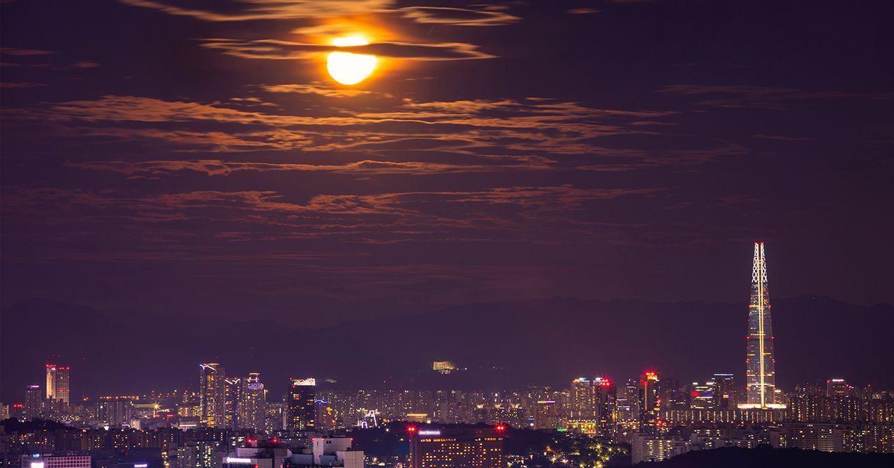 首尔夜景，全景可以看到明亮的建筑和满月。