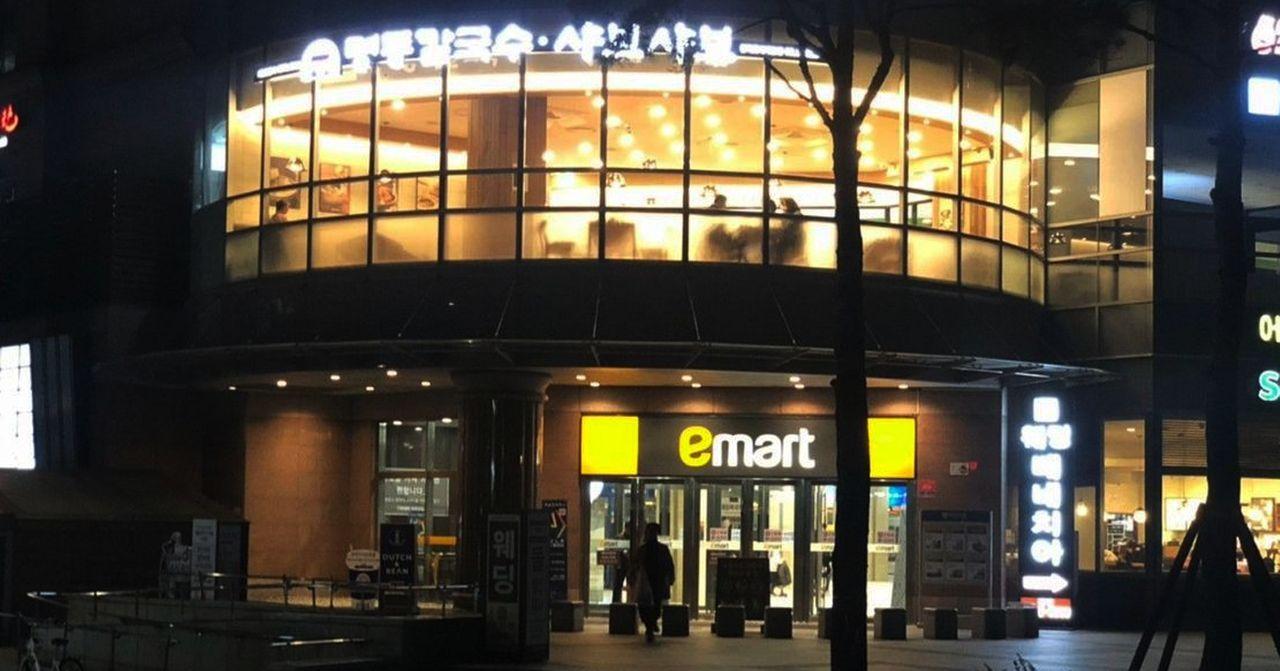 夜晚的乐天超市门口，购物者出入其中，店内灯火通明。