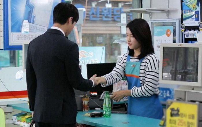 便利店柜台的韩国顾客与店员握手