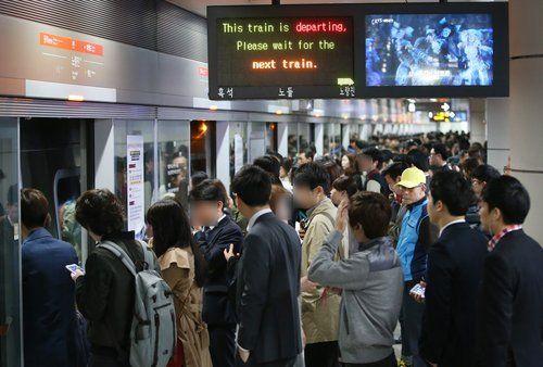 首尔地铁站台上，有许多人在等候列车。
