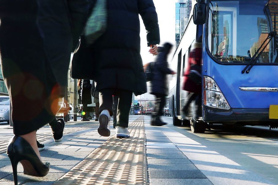 붐비는 도심의 거리 모습으로, 사람들이 버스에 오르내리는 활동을 보여준다.