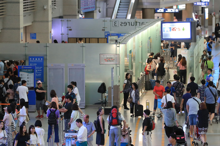 복잡한 공항 대합실의 모습으로, 국제선 이용객들이 줄지어 서 있는 장면이다.