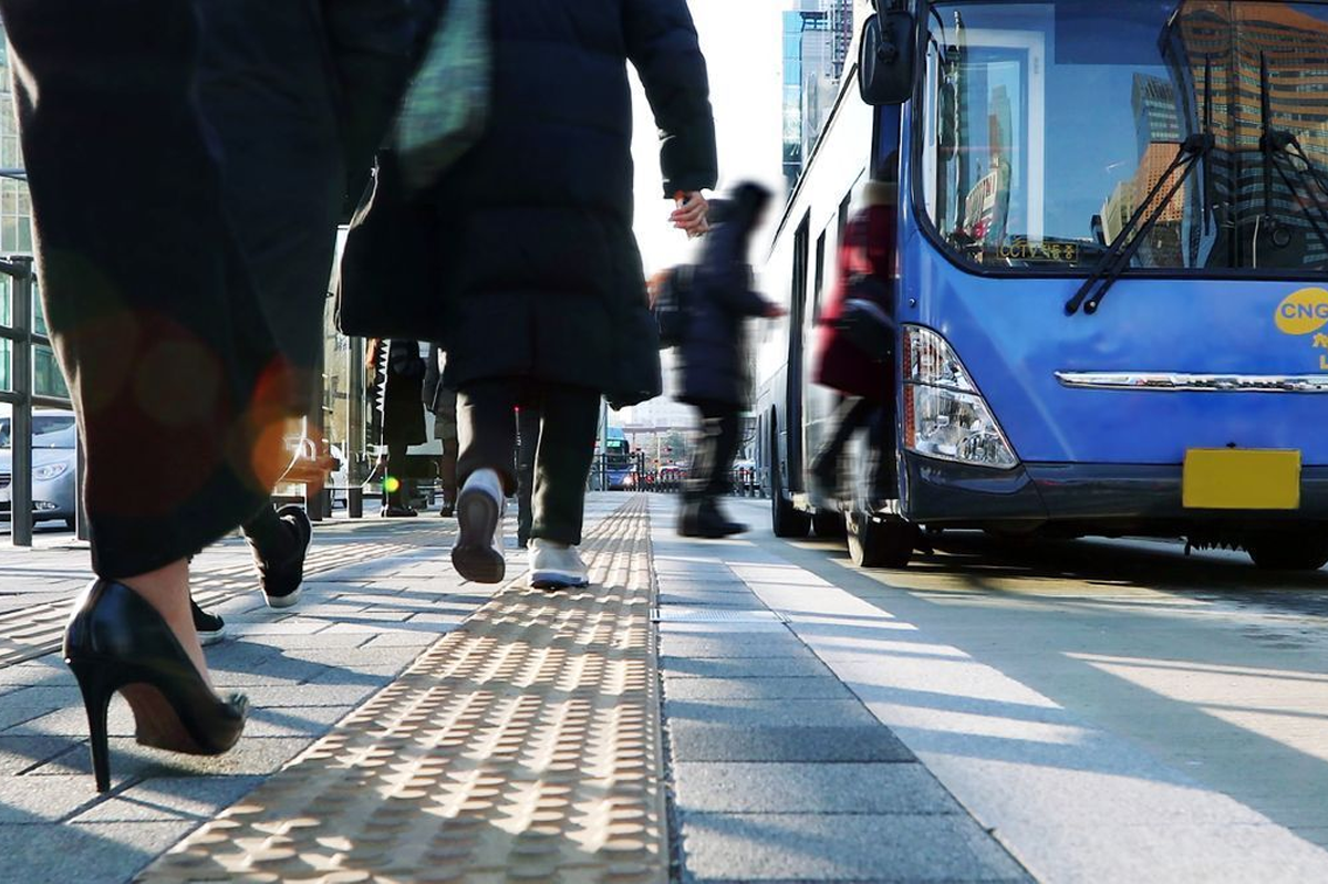 城市中行走的人羣和公交車，展示繁忙的都市生活。