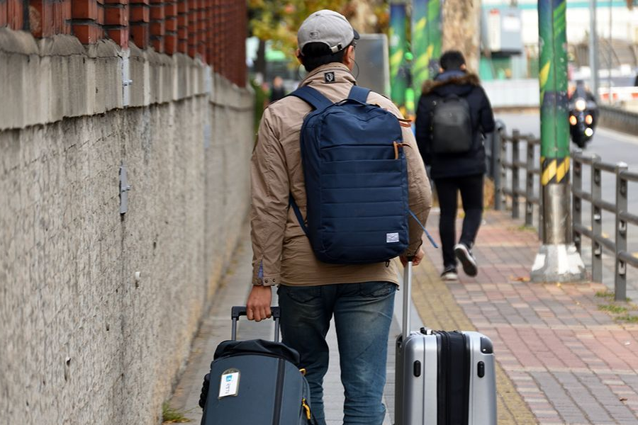 여행자의 모습으로, 짐가방을 들고 길을 걷는 사람의 뒷모습을 담은 이미지이다.