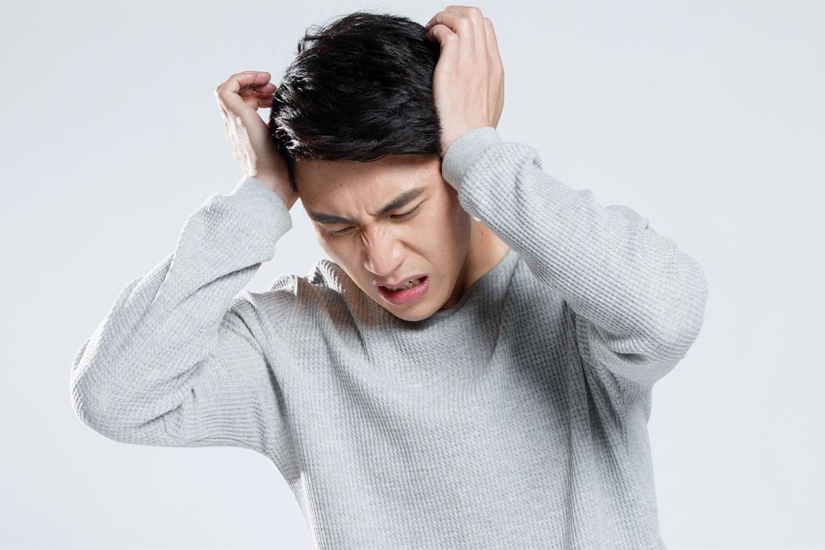 Hình ảnh một người đàn ông đang ôm đầu, minh họa tình trạng đau đầu trong bài viết về từ vựng tiếng Hàn liên quan đến đau đầu khi du lịch ở Hàn Quốc.
