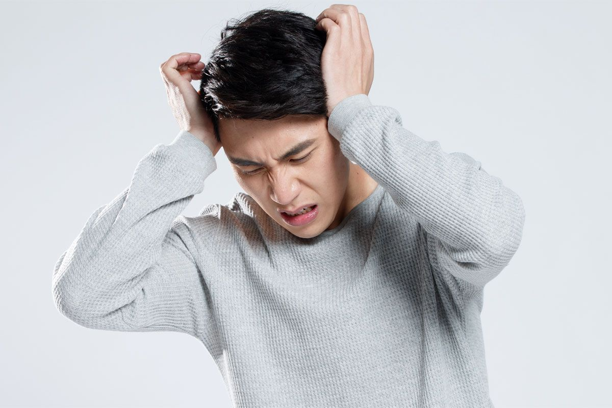 頭を押さえる男性のイメージ。頭痛の症状を表現。