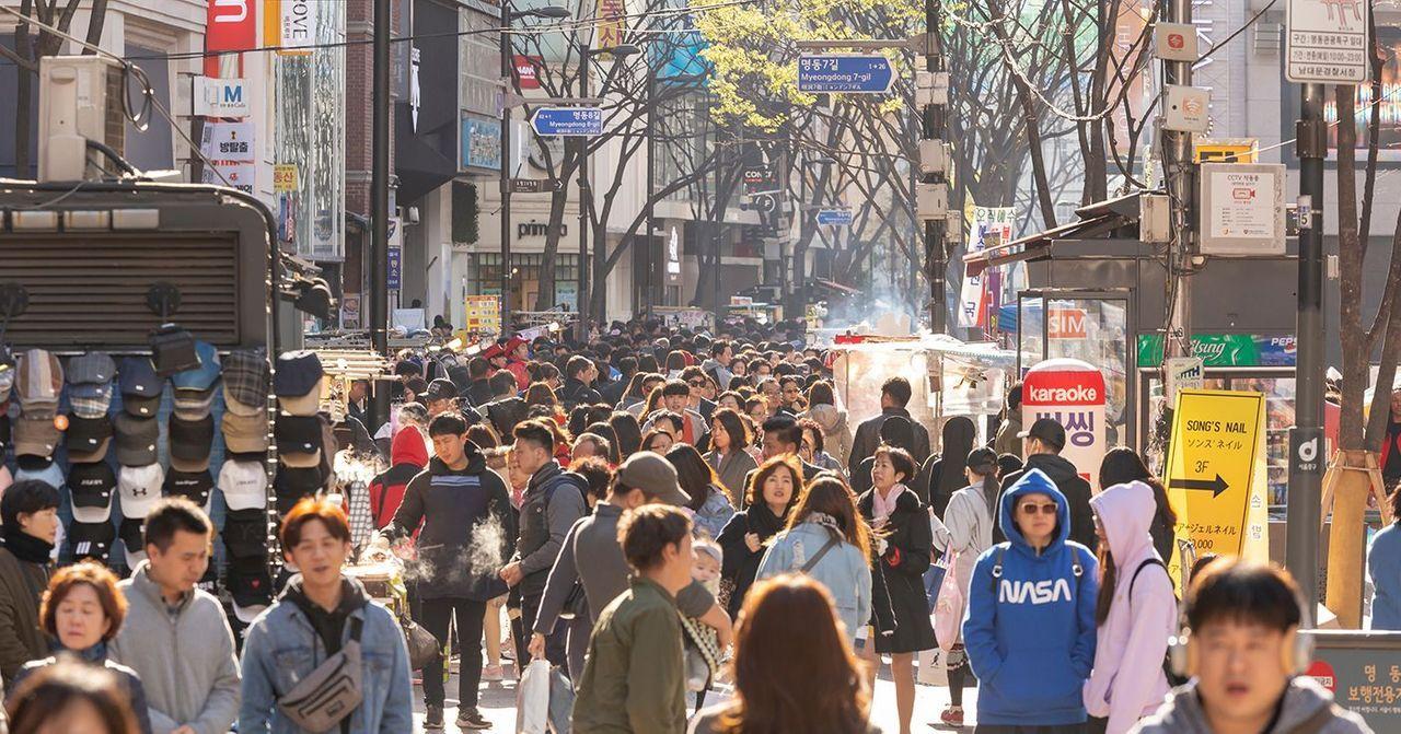 首爾明洞街道上的人群，擁擠的市場和充滿活力的城市生活。