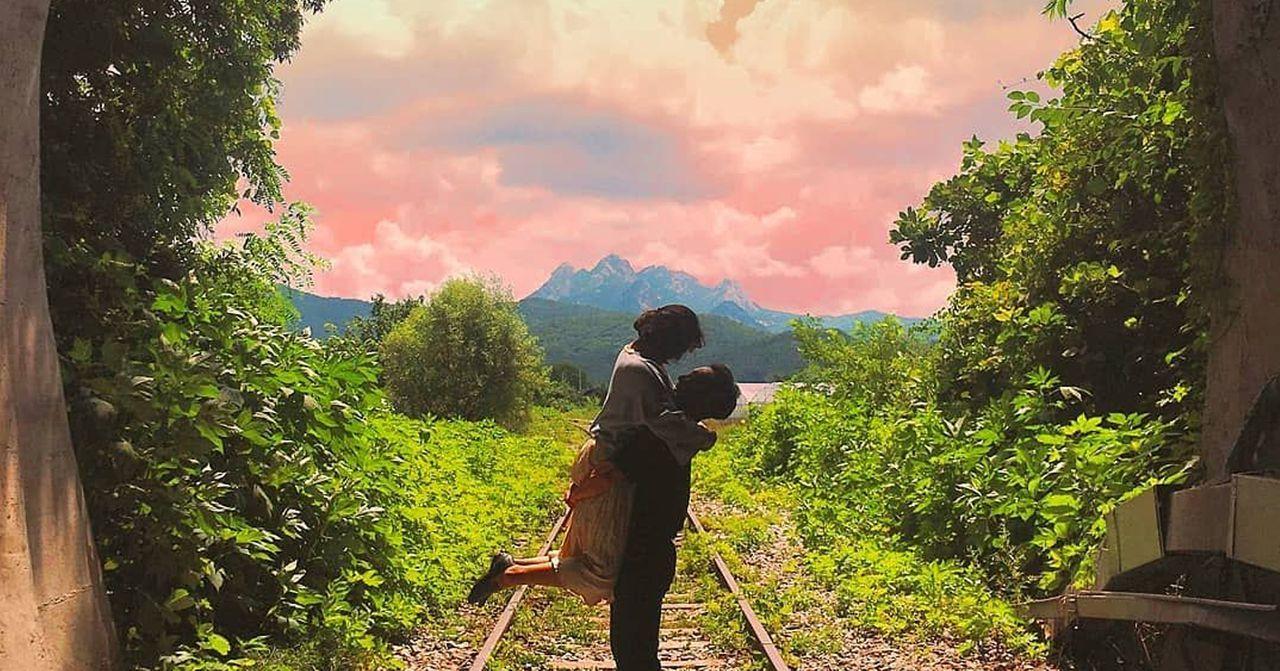 絕美隧道打卡點，兩位行人在夕陽的映照下，背景是迷人的粉紅色天空和山景。