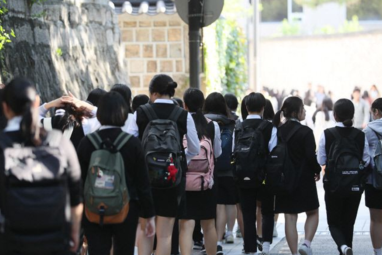 一羣穿著校服的學生們正行走在校園裡，代表學校生活的壓力與活力