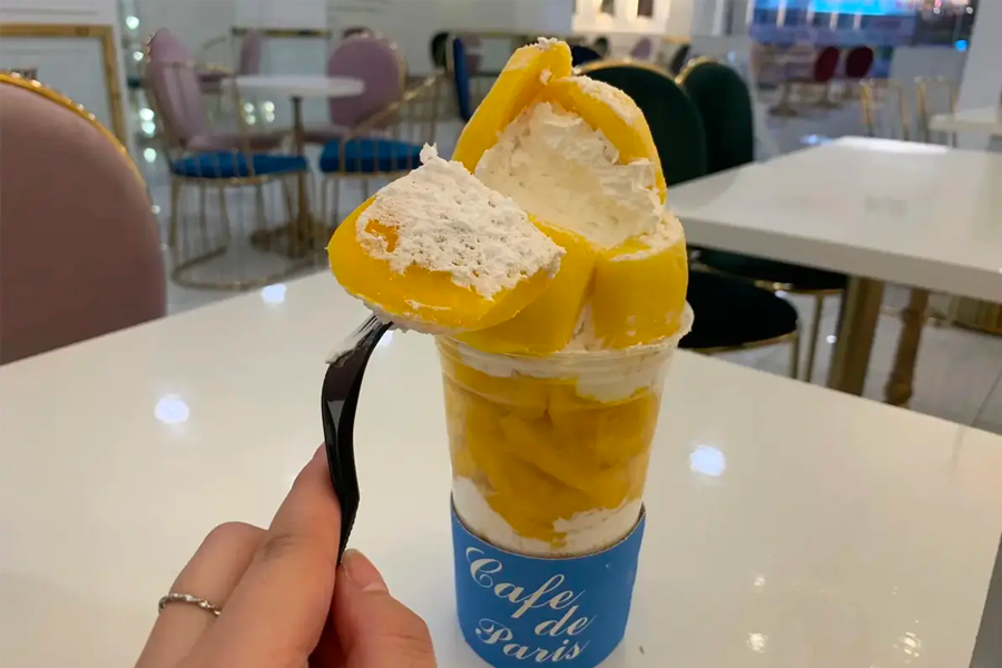 카페 드 파리에서 인기 있는 망고 봉봉 디저트의 모습으로, 손으로 들고 있는 모습입니다.