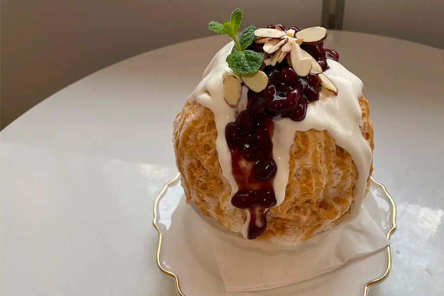 제주 녹차 빙수의 모습으로, 녹차를 듬뿍 얹고 크림과 함께 장식된 빙수입니다.