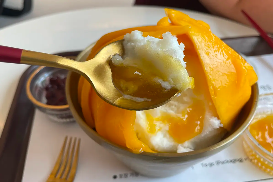 리얼 망고 빙수와 함께 제공되는 다른 토핑들과 아이스크림, 과일 소스가 그릇에 놓인 모습입니다.