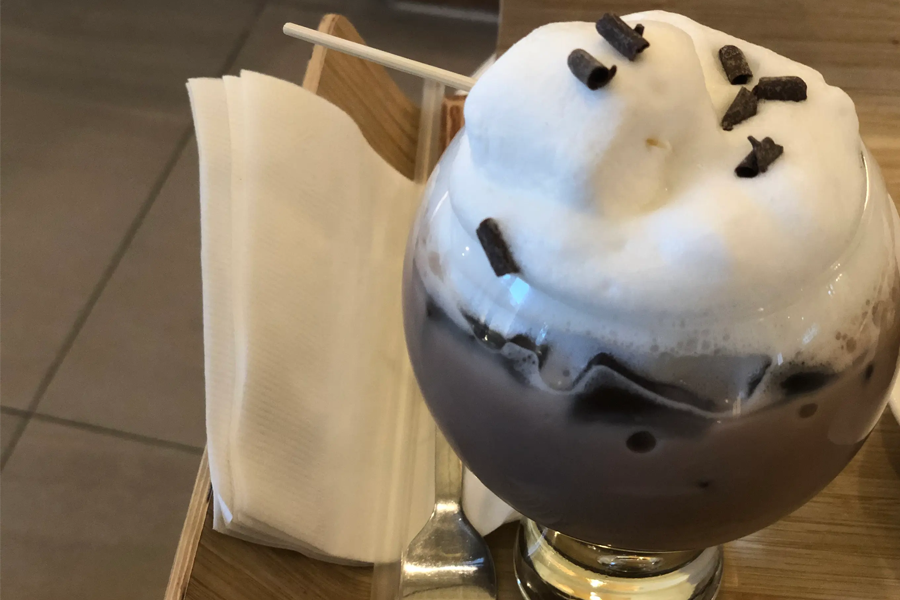 一杯顶部覆盖着奶油的巧克力拿铁，放在一个托盘上