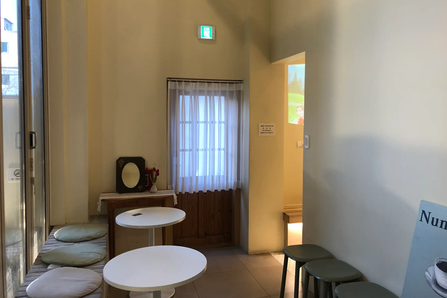 Tag One咖啡厅中长椅靠窗区，装饰有现代感的墙绘和装饰品