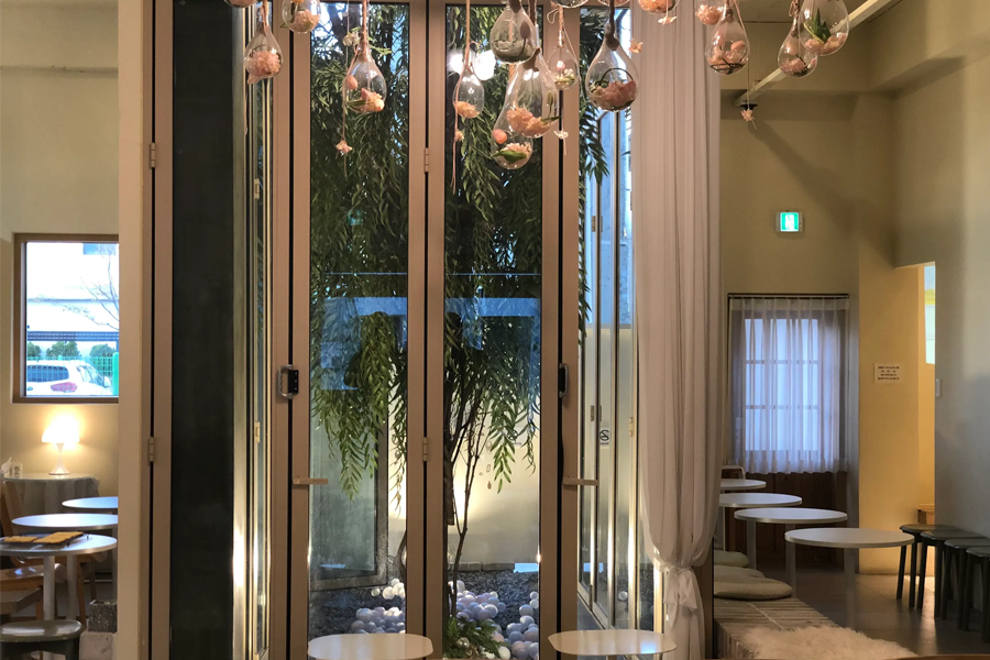 装饰着吊灯的Tag One咖啡厅内部区域，通透的玻璃墙处可见窗外景色