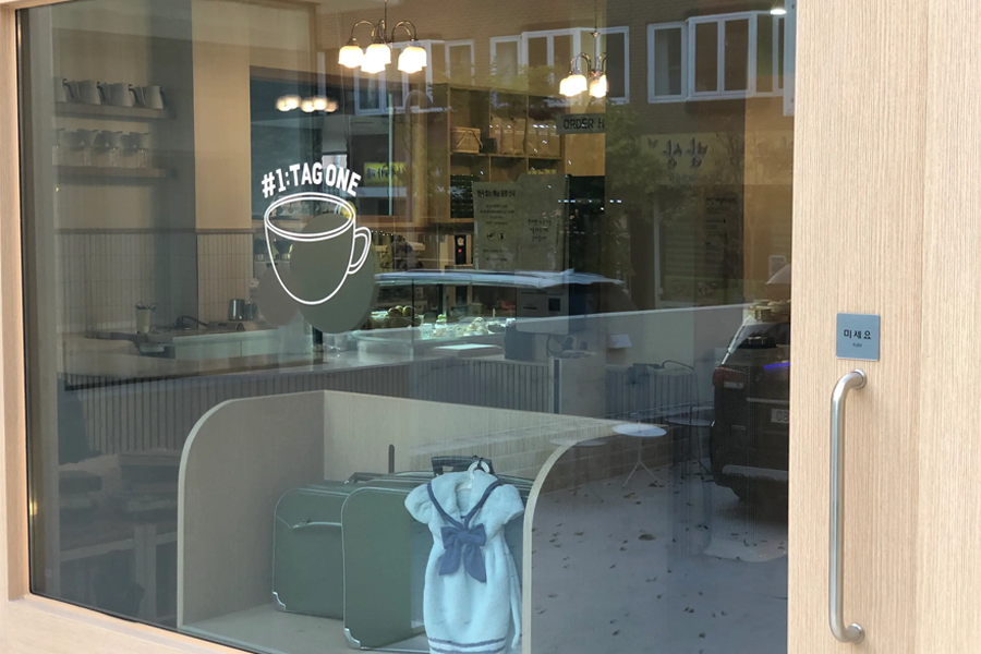 清州Tag One咖啡厅的玻璃门，门上印有咖啡杯图案和#1 Tag One的标识