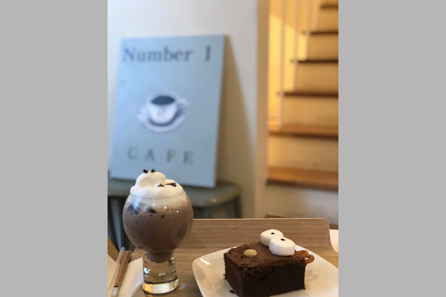 Tag One咖啡厅里的甜品：巧克力拿铁和布朗尼蛋糕，背景为楼梯和装饰画