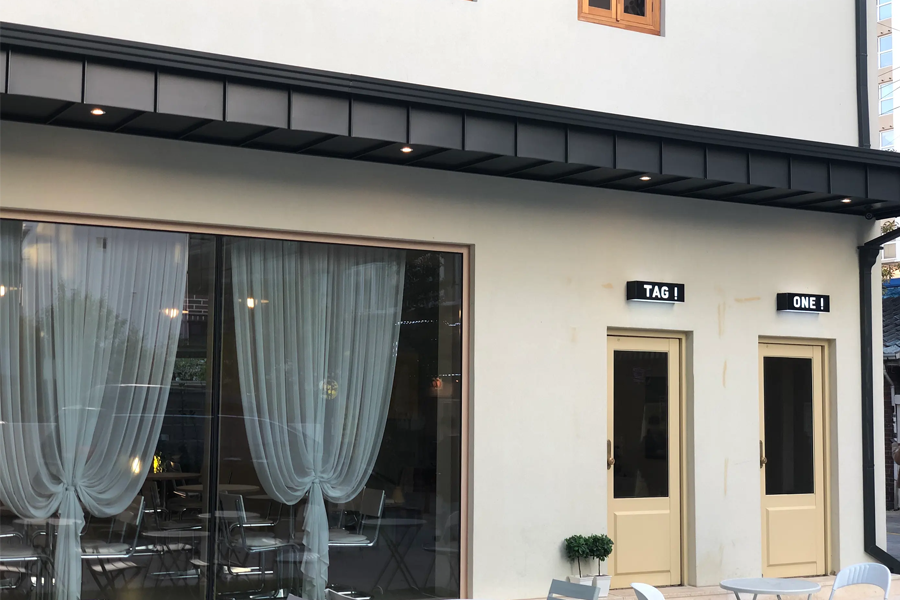 Tag One别馆的外观，入口处有舒适的座位和绿植装饰