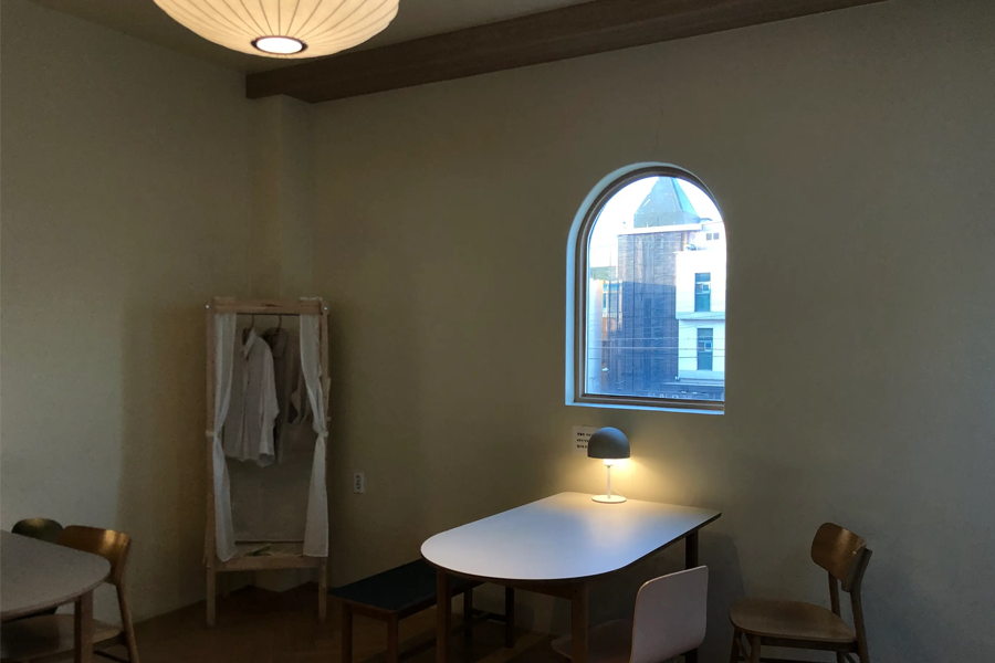 Tag One咖啡厅中一个靠窗口的小桌，旁边有晾衣架和桌灯