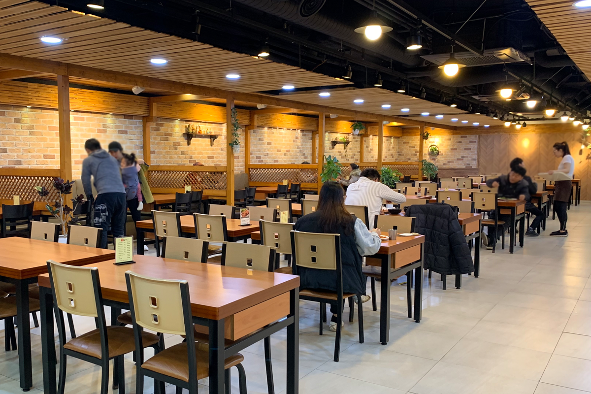 一家人正在釜山南浦洞Kongbate韓式半自助餐廳用餐的室內環境照片，展示寬敞的座位和温暖的燈光。