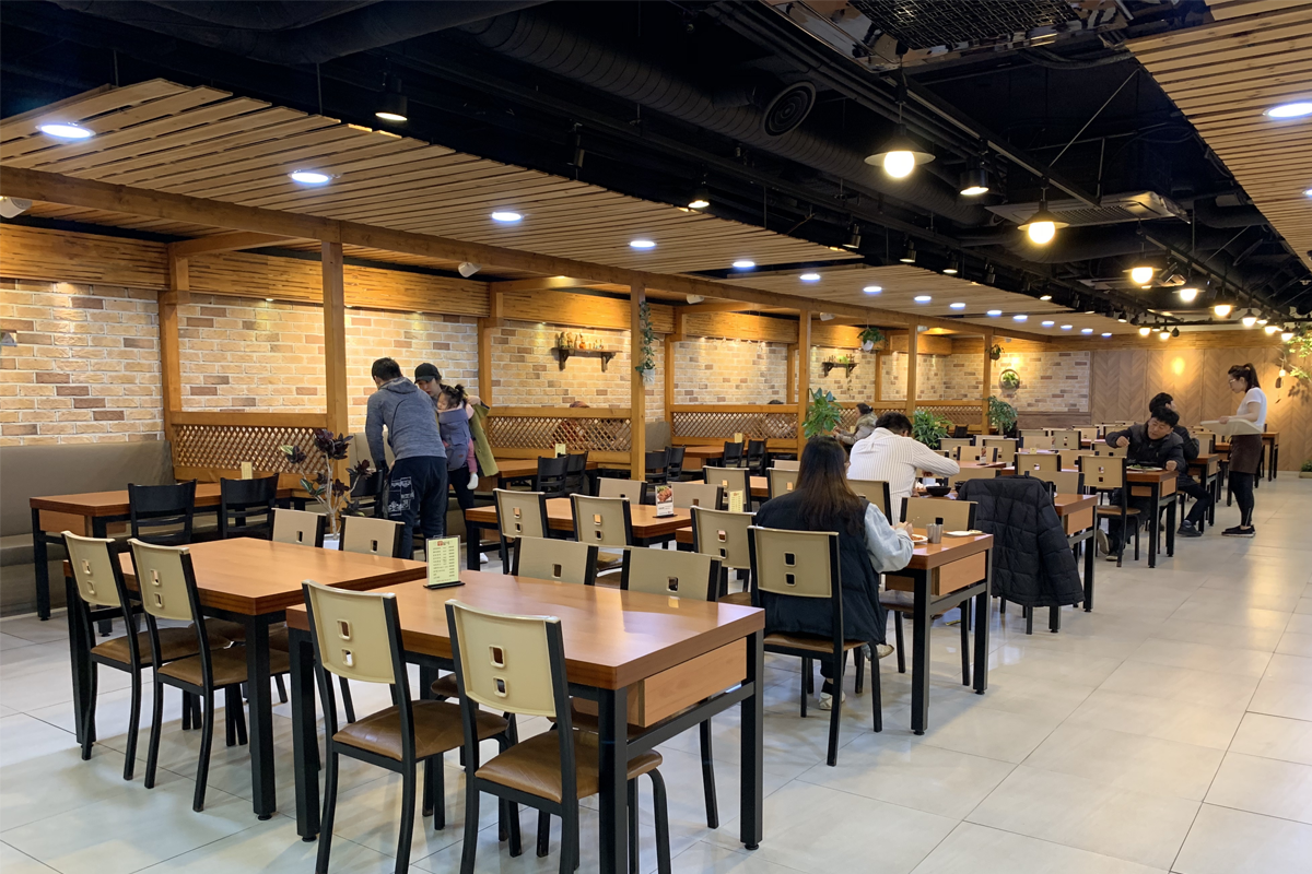 豆田里餐厅内风格宽敞明亮的用餐区，摆放着许多餐桌和椅子，客人们正在享用餐点。