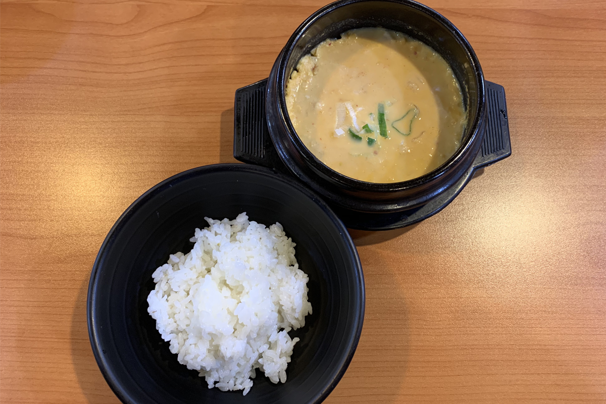 豆田里餐厅的一道韩式餐，包含嫩豆腐锅和米饭，餐具布置感整齐。
