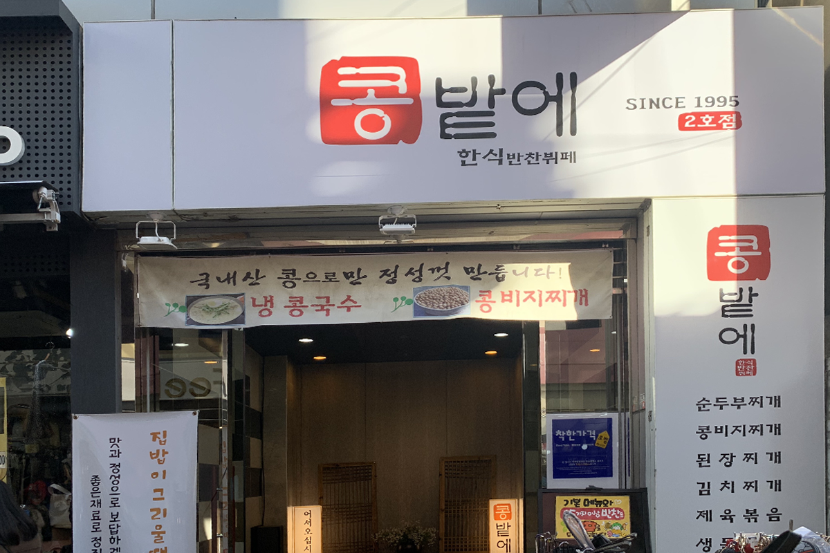 豆田里餐厅正门外观，一块招牌高挂，展示有多种美味韩式料理的广告。