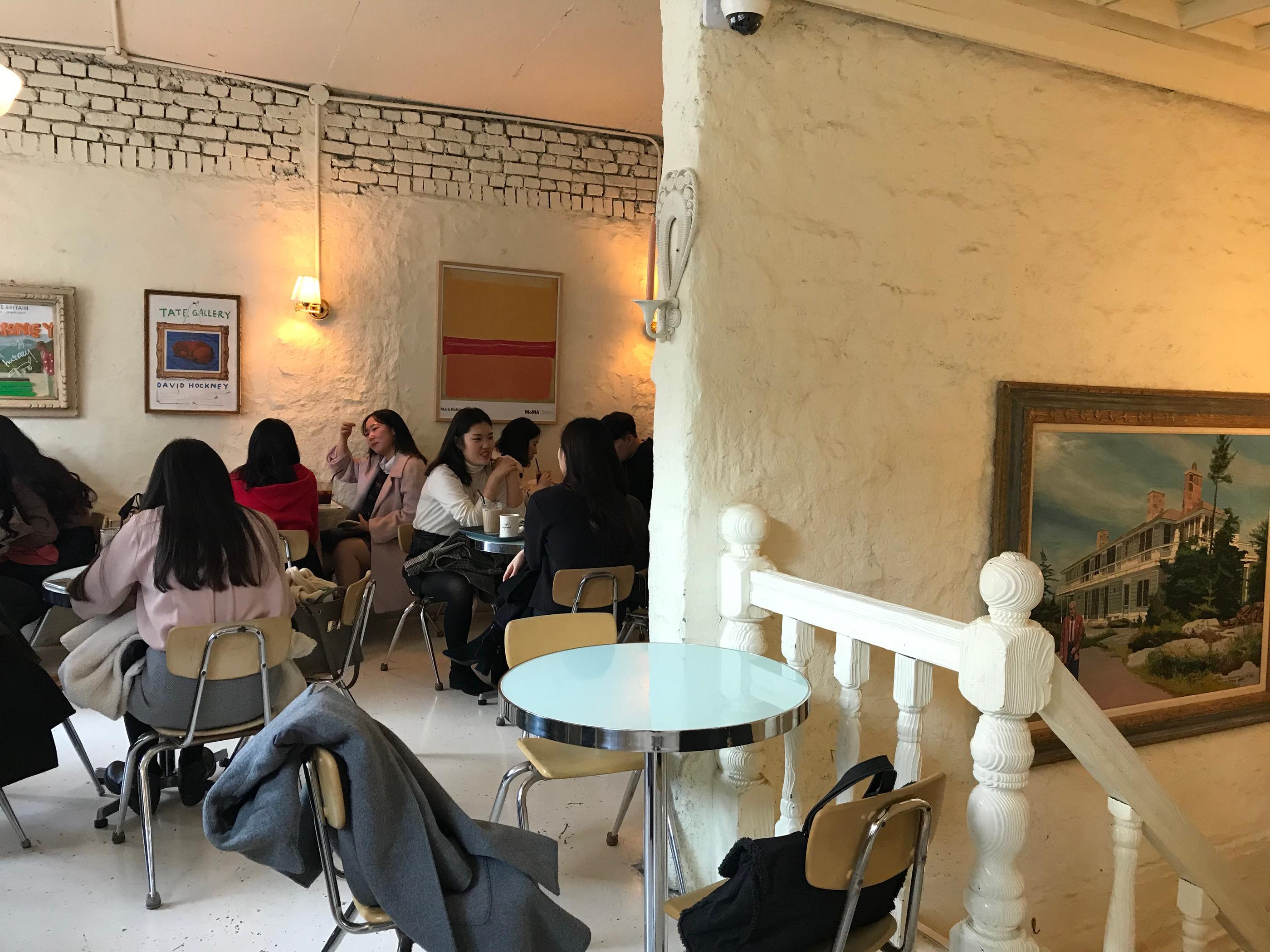 ภายใน Cafe Layered ที่เต็มไปด้วยรายละเอียดการตกแต่งในโทนสีขาวและโคมไฟอบอุ่น