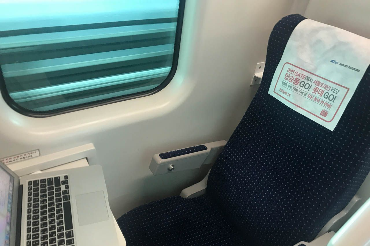 AREX直通列車のコンパートメント内の座席とテーブル。コンパクトにノートパソコンを広げて作業ができ、乗車中の快適な環境を提供している。ソウルと仁川国際空港をつなぐ最速の交通手段です。