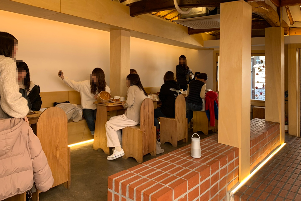 익선동에 위치한 밀 토스트 하우스의 내부 모습. 많은 손님들이 음식을 즐기며 대화하고 있다.