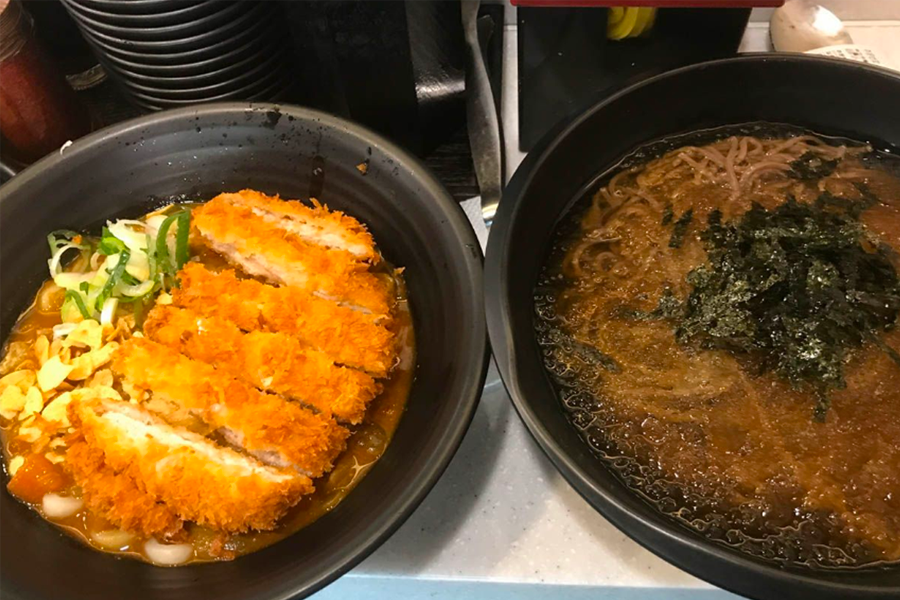 站前烏龍店內美食特寫,展示配有蔥花、海苔和胡椒的熱騰騰烏龍湯麵。